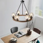 Farmhouse style meets modern minimalist on this Crystal Wood Flyer Chandelier. This vintage-style linear chandelier is compatible with sloped ceilings. 6 irregularly shaped glass lampshade perches on the wooden round base, each designed to house an E12 candelabra base bulb (not included) that adds a candle style to this linear chandelier. Let the warm glow of this embrace you with this farmhouse kitchen island chandelier rustic matte black and wood-like finish.