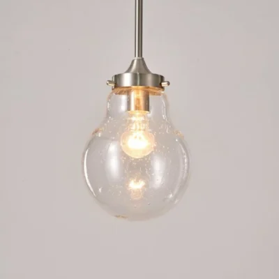 This pendant light features a transparent glass shade that adds a touch of elegance and sophistication to your room. Connected to the base is a sleek silver iron tube that is adjustable, allowing you to customize the height of the pendant to suit your preference.