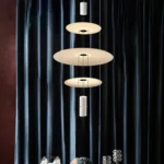 This pendant light has a light source at each end and three frosted glass discs in the center, which allows for better light distribution.