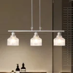 A minimalist masterpiece that seamlessly blends captivating design with functional brilliance, this chandelier transcends the ordinary. Featuring hand-blown glass pendant that commands attention from above, this chandelier will effortlessly accent a space of any size. Suspended elegantly from a sleek metal, the chandelier allows light to playfully dance within its clear glass confines, creating a mesmerizing interplay of shadows and illumination. Combining high-quality metal construction and adjustable height functionality, this pendant light fixture offers a unique lighting experience.